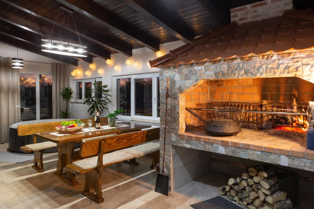 a kitchen with a large stone fireplace with a wooden table at Kuća za odmor 'Teuta' in Vrhovine