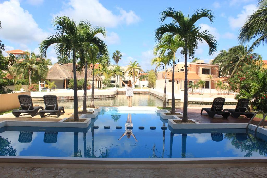 a person swimming in a pool with palm trees at Hermosa Mansión en Puerto Aventuras con alberca in Puerto Aventuras