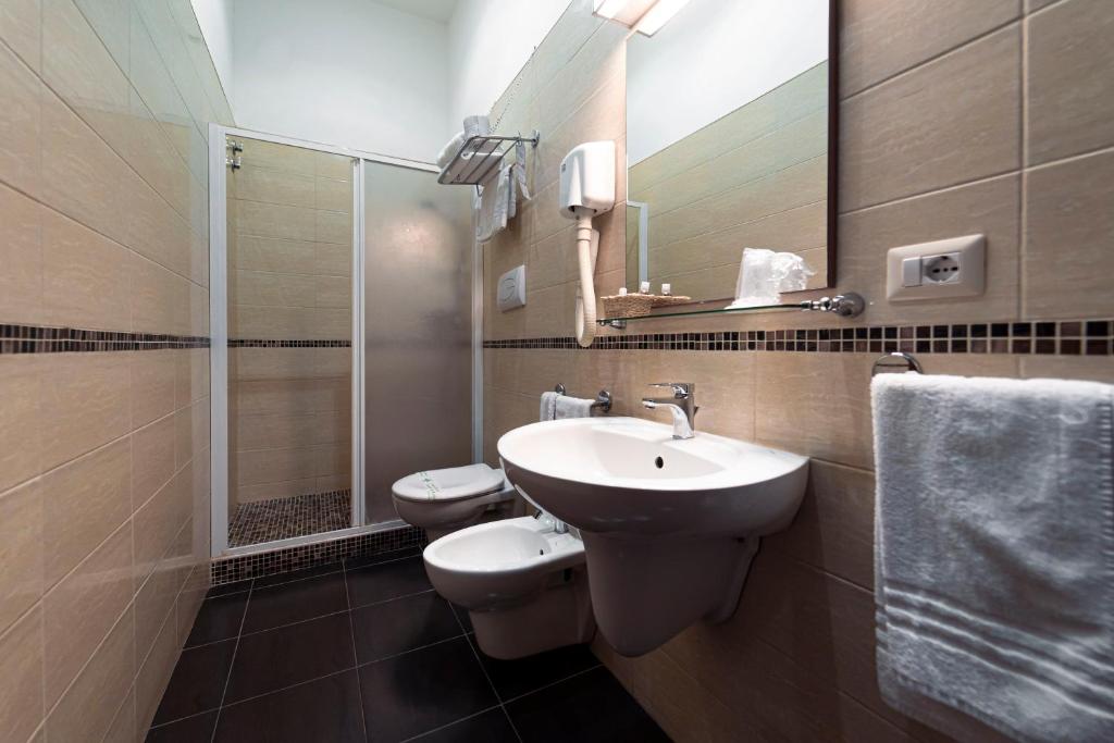 a bathroom with a sink and a toilet and a mirror at Hotel Villa Romeo in Catania