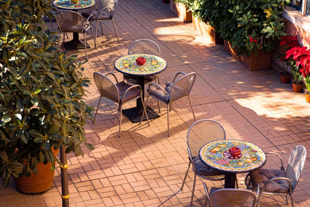 a patio with tables and chairs with flowers on them at Hotel Villa Romeo in Catania