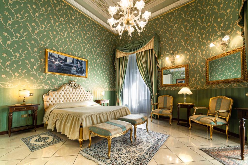 a bedroom with a bed and chairs and a chandelier at Hotel Villa Romeo in Catania