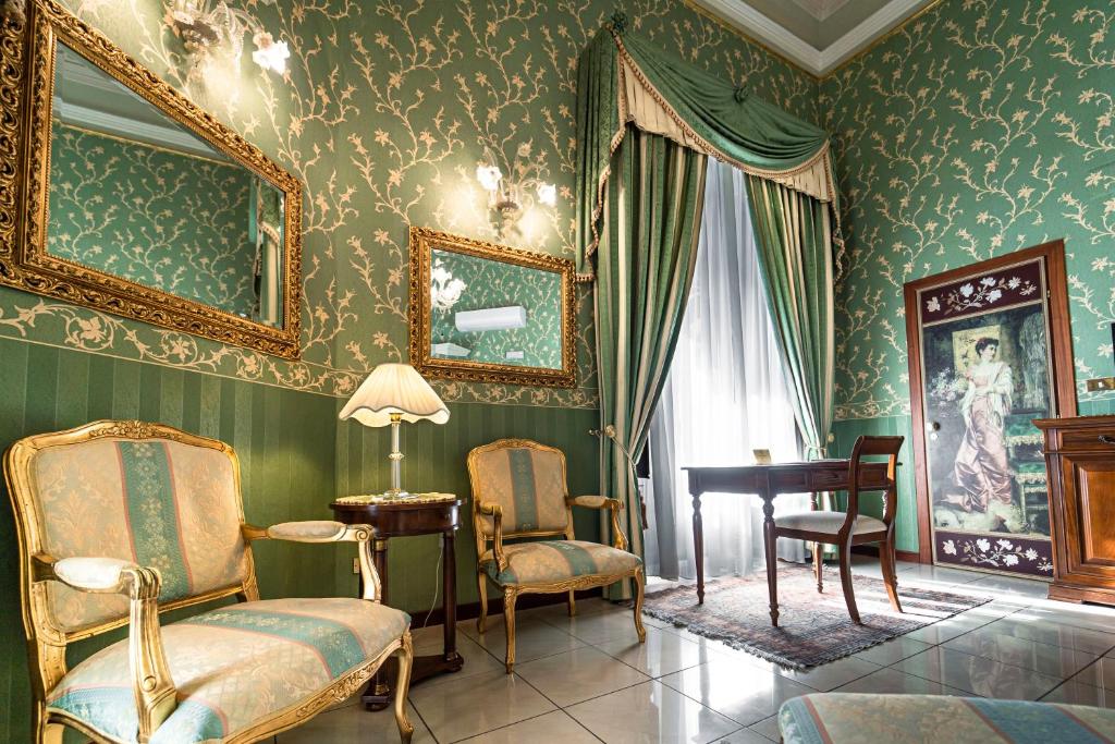 a room with green wallpaper with a table and chairs at Hotel Villa Romeo in Catania