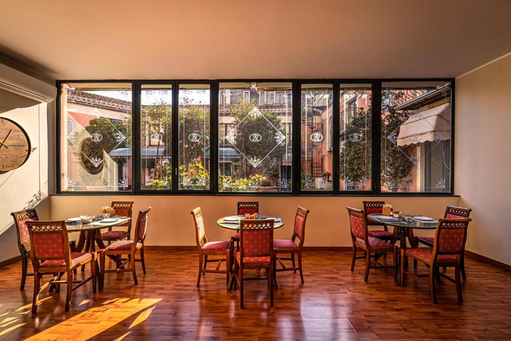 a restaurant with tables and chairs and large windows at Hotel Villa Romeo in Catania
