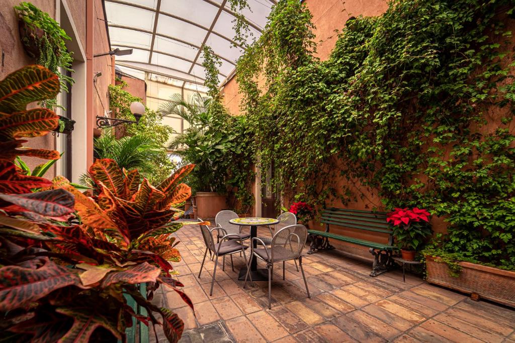 a patio with a table and chairs in a greenhouse at Hotel Villa Romeo in Catania
