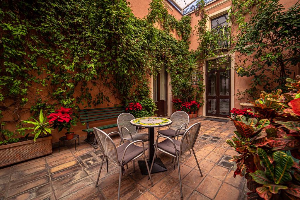 a patio with a table and chairs and a bench at Hotel Villa Romeo in Catania