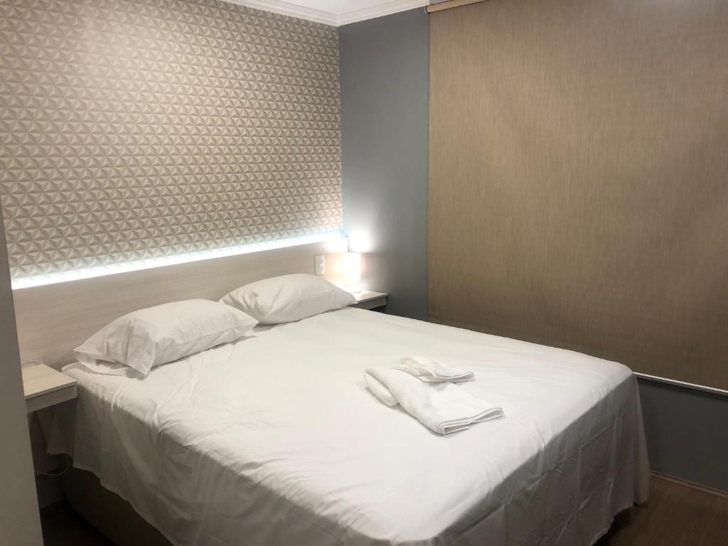 a bedroom with a white bed with two towels on it at Loft aconchegante com piscina a um passo do metrô in Sao Paulo