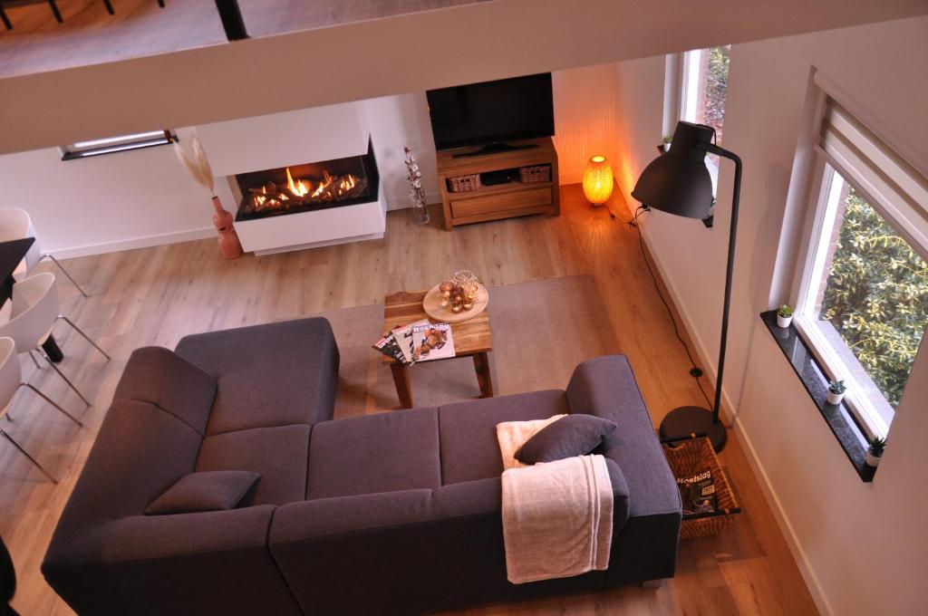 een woonkamer met een bank en een open haard bij Vakantiehuisje Opdekamp in Merselo