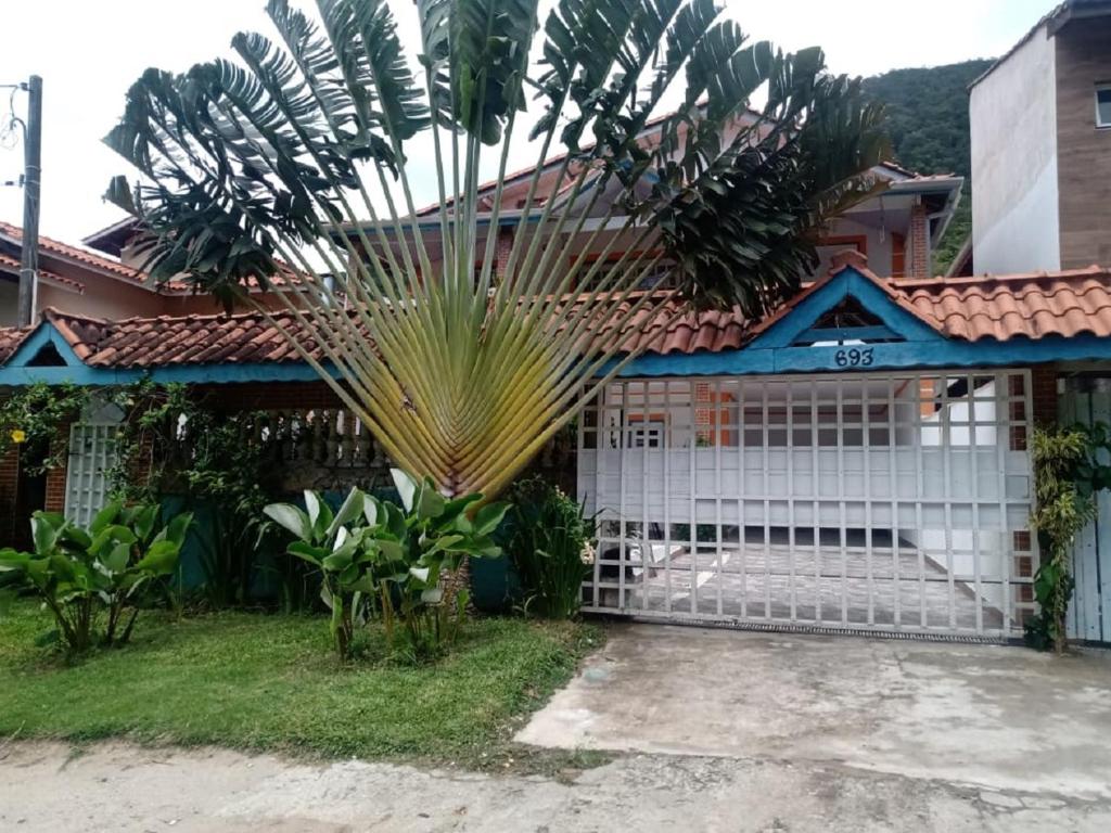 a white gate in front of a house with a palm tree at Casa com Piscina em Barequeçaba in São Sebastião