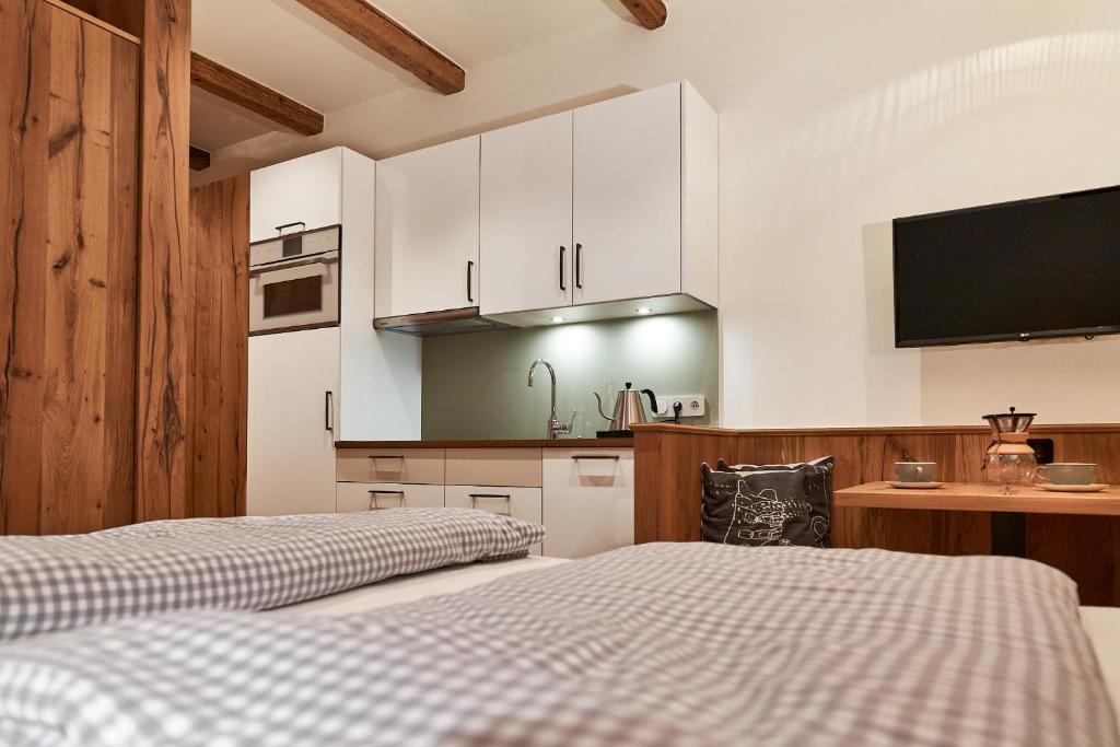 a bedroom with two beds and a kitchen with white cabinets at Berghaus Schröcken - Hotel Apartments Spa in Schröcken