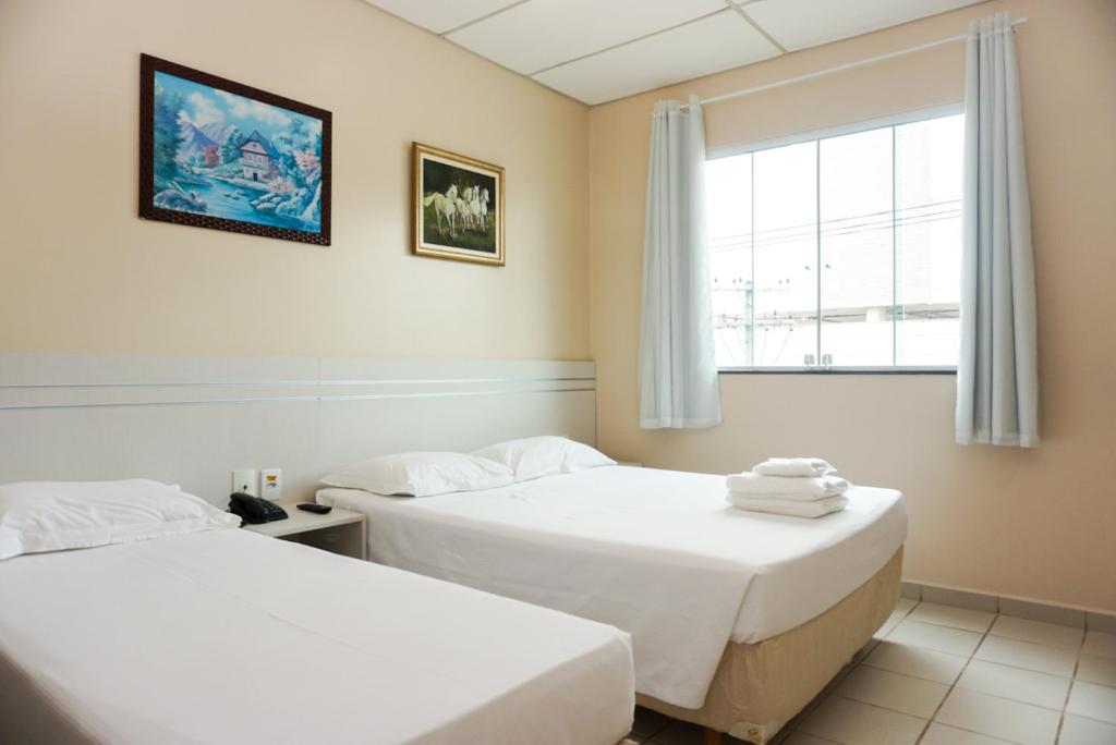 2 camas en una habitación con ventana en Lord Hotel Camburi, en Vitória