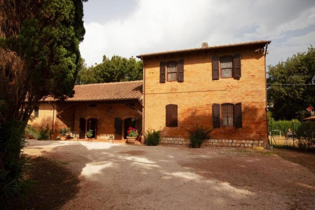 een groot bakstenen huis met een oprit ervoor bij Casale Alessandra, villa storica della Maremma in Principina a Mare