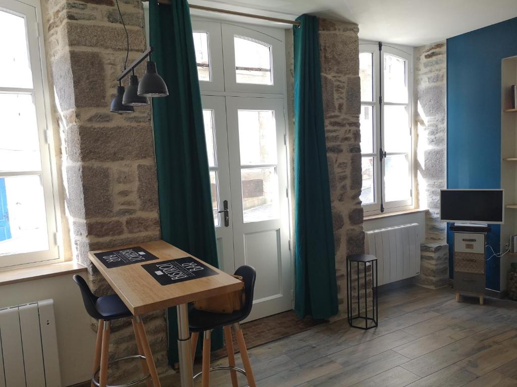 um quarto com uma mesa, cadeiras e janelas em Haute ville : studio ravissant em Granville