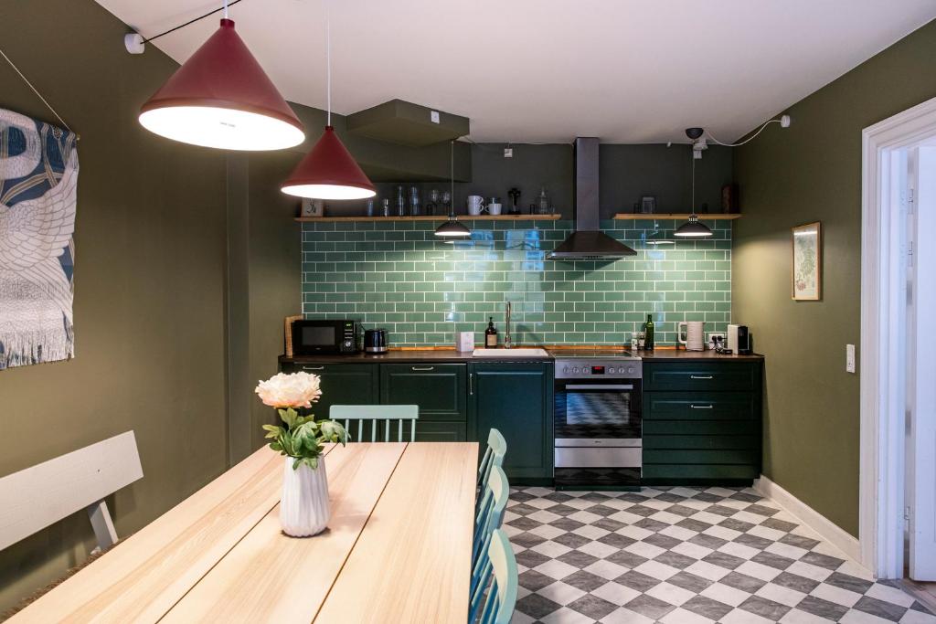 una cocina con armarios verdes y una mesa con un jarrón de flores en The Churchill 4 by Daniel&Jacob's, en Copenhague