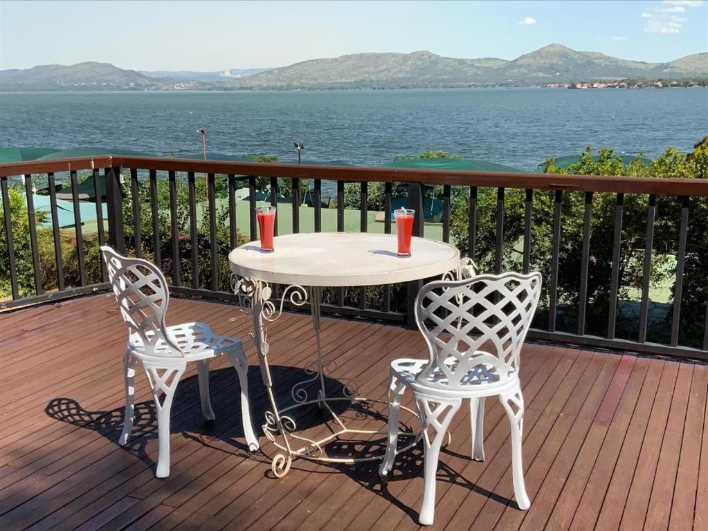 a table and two chairs on a deck with the water at Marina Views Guesthouse in Hartbeespoort