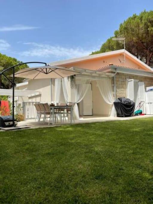 dom ze stołem i parasolem na dziedzińcu w obiekcie Zaffiro casa vacanze al mare w mieście Valledoria