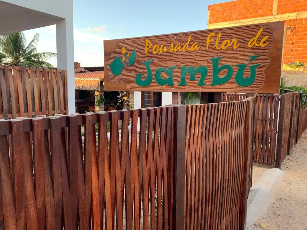 a wooden fence with a sign in front of a restaurant at Pousada Flor De Jambú in São Miguel do Gostoso