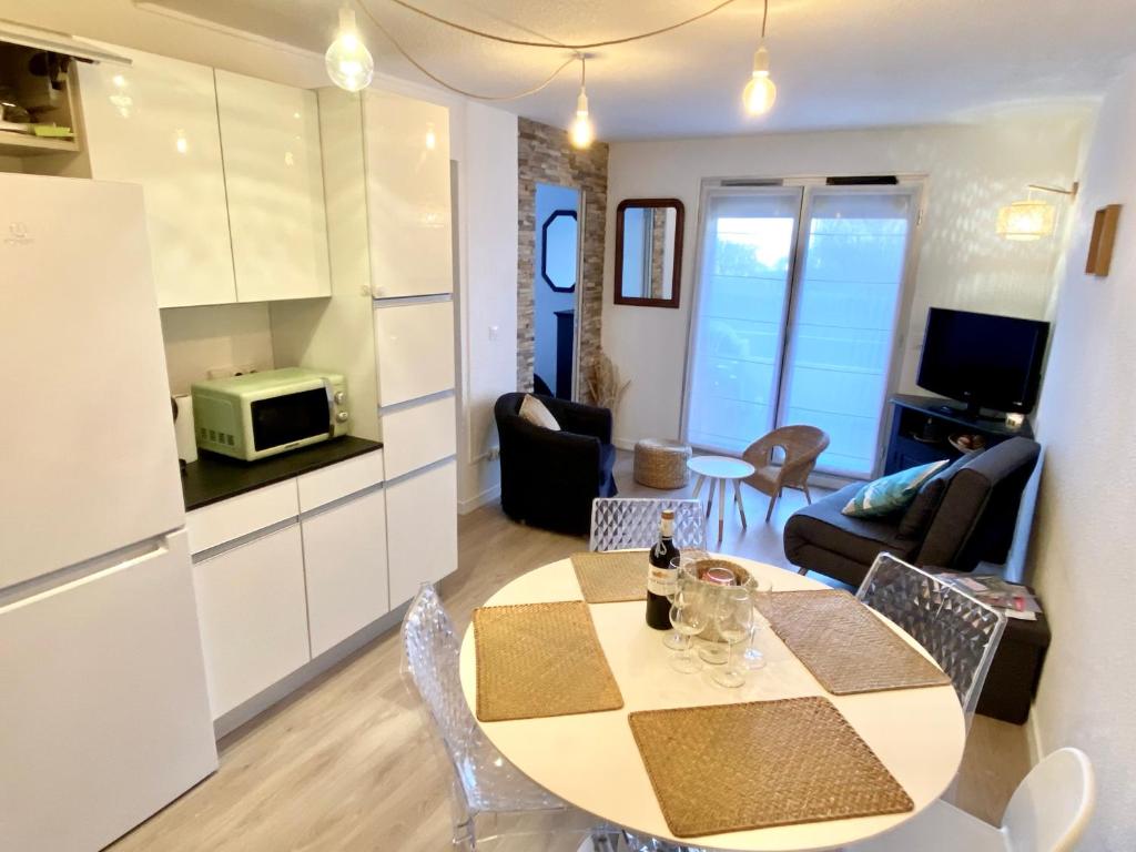 une cuisine et un salon avec une table et des chaises dans l'établissement Chez Alix et Jo Superbe T3 au bord de l’Océan, à Lacanau