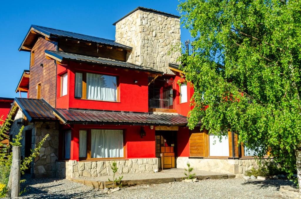 uma casa vermelha com uma árvore em frente em Kurtem Lodge em San Carlos de Bariloche