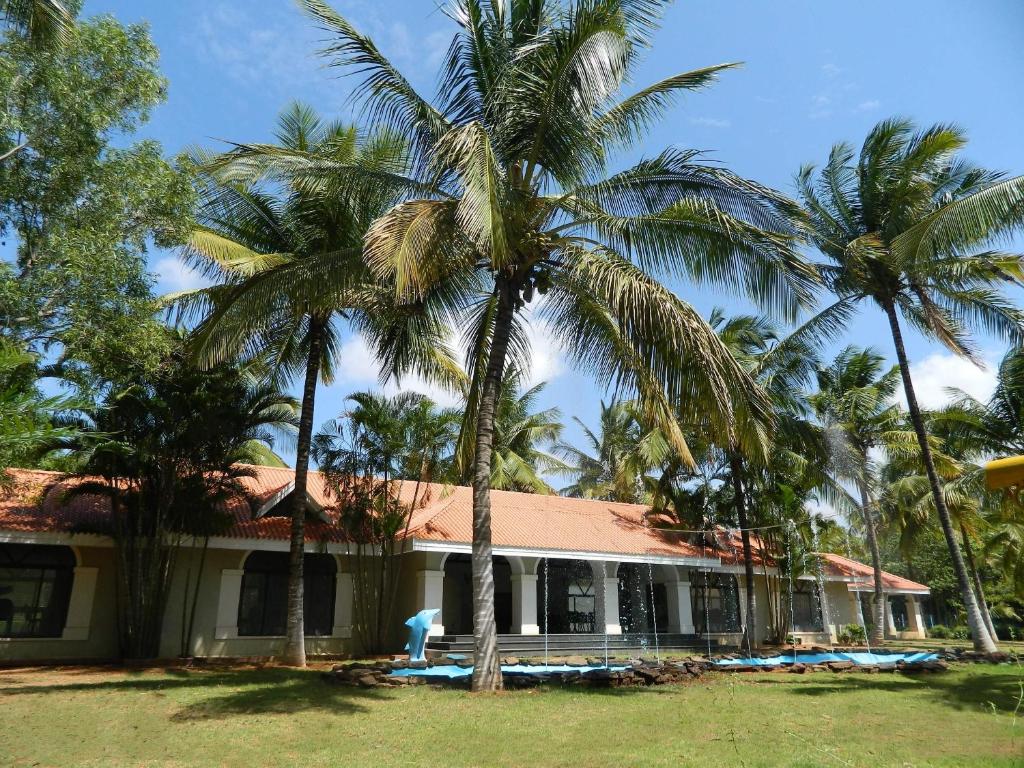 a house with palm trees in front of it at Fantasy Golf Resort in Devanhalli