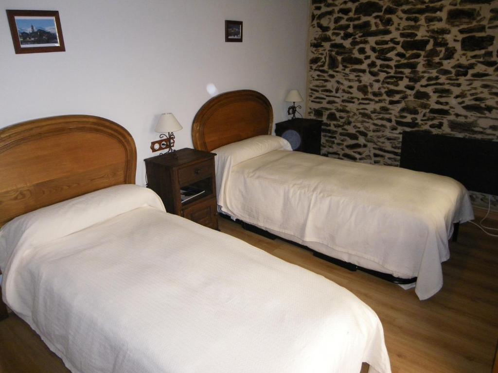 a bedroom with two beds and a stone wall at Casa Rural Los Cabritos de Tomás in Puebla de Sanabria
