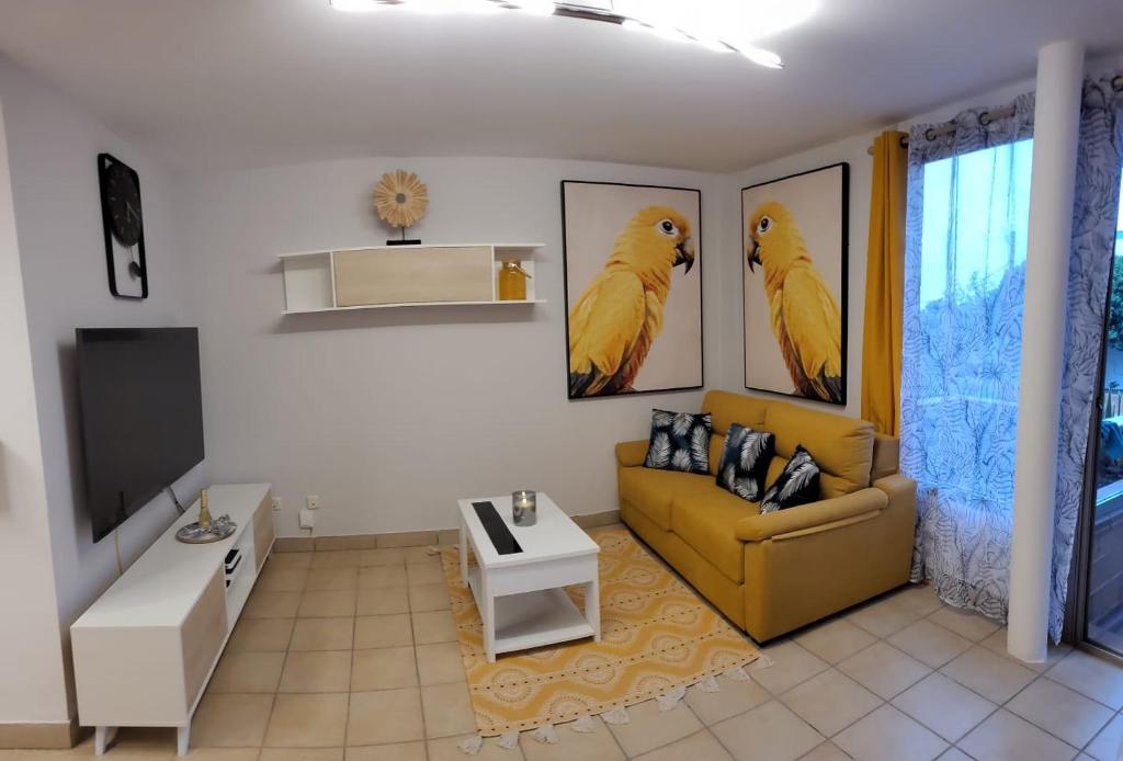 - un salon avec un canapé jaune et deux oiseaux sur le mur dans l'établissement Residencial Esquinzo 2, à Playa Jandía