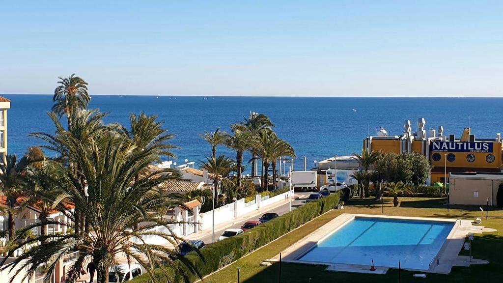 a view of a resort with a swimming pool and the ocean at Beach Front Sea View Punta Prima in Punta Prima