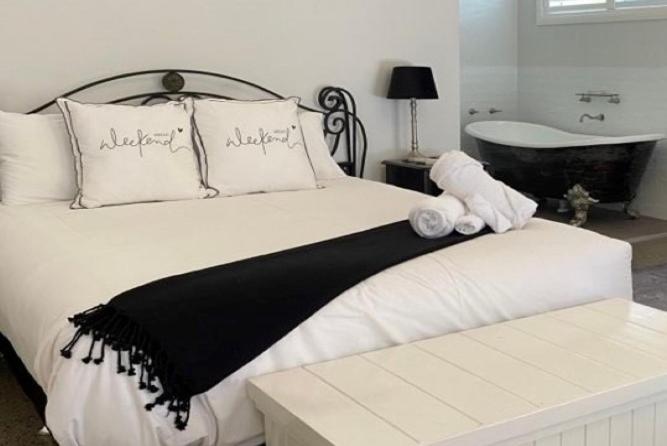 a bed with a black and white blanket and a bath tub at Chez Vous French Farmhouse Villa 4 in Pokolbin