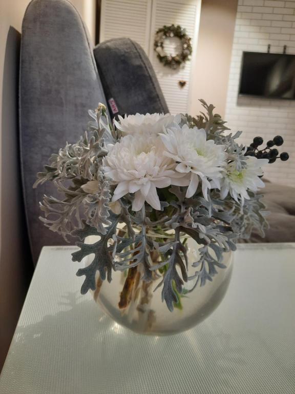 a vase filled with white flowers on a table at super apartment on O.Polya 137 in Dnipro