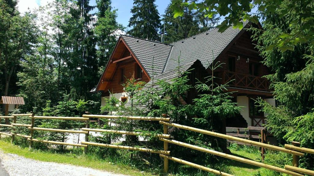 a wooden house with a fence in front of it at Chata Alpina in Ružomberok