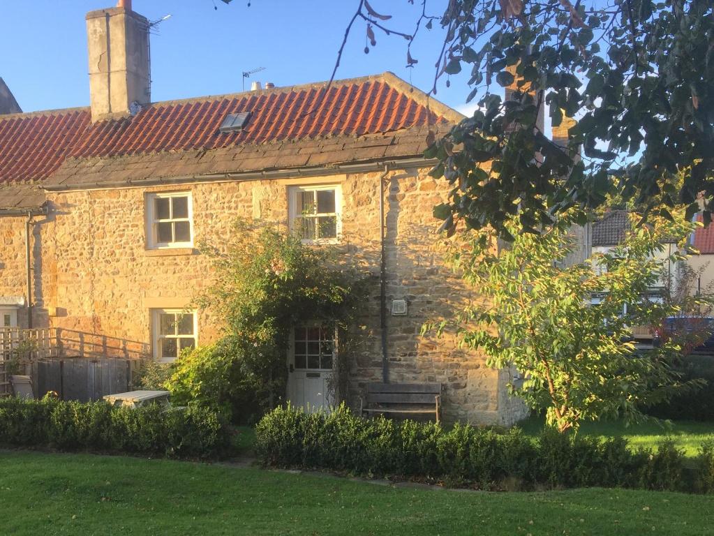 a brick house with a bench in front of it at Corner Cottage in Staindrop