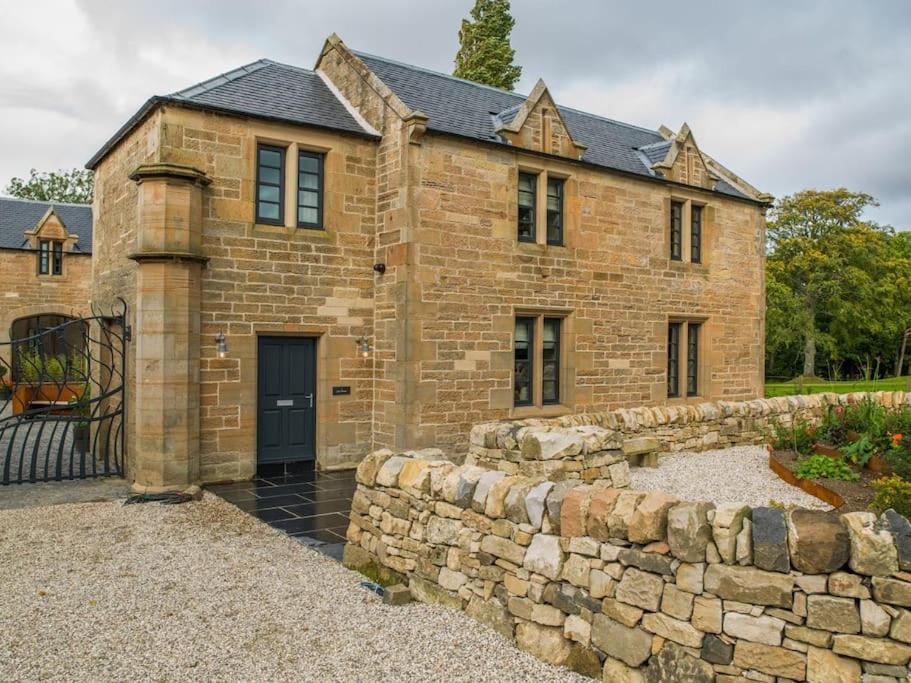 uma grande casa de tijolos com uma parede de pedra em Stunning Edinburgh 1820s stables converted house em Ratho