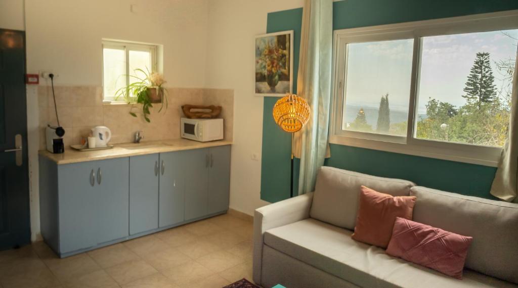 a living room with a couch and a kitchen with a window at Beit Oren Hotel in Beit Oren