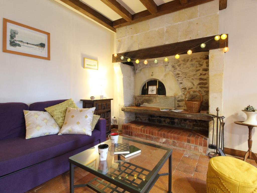 a living room with a purple couch and a stone fireplace at Gîte Blaison-Saint-Sulpice, 2 pièces, 3 personnes - FR-1-622-23 in Saint-Sulpice