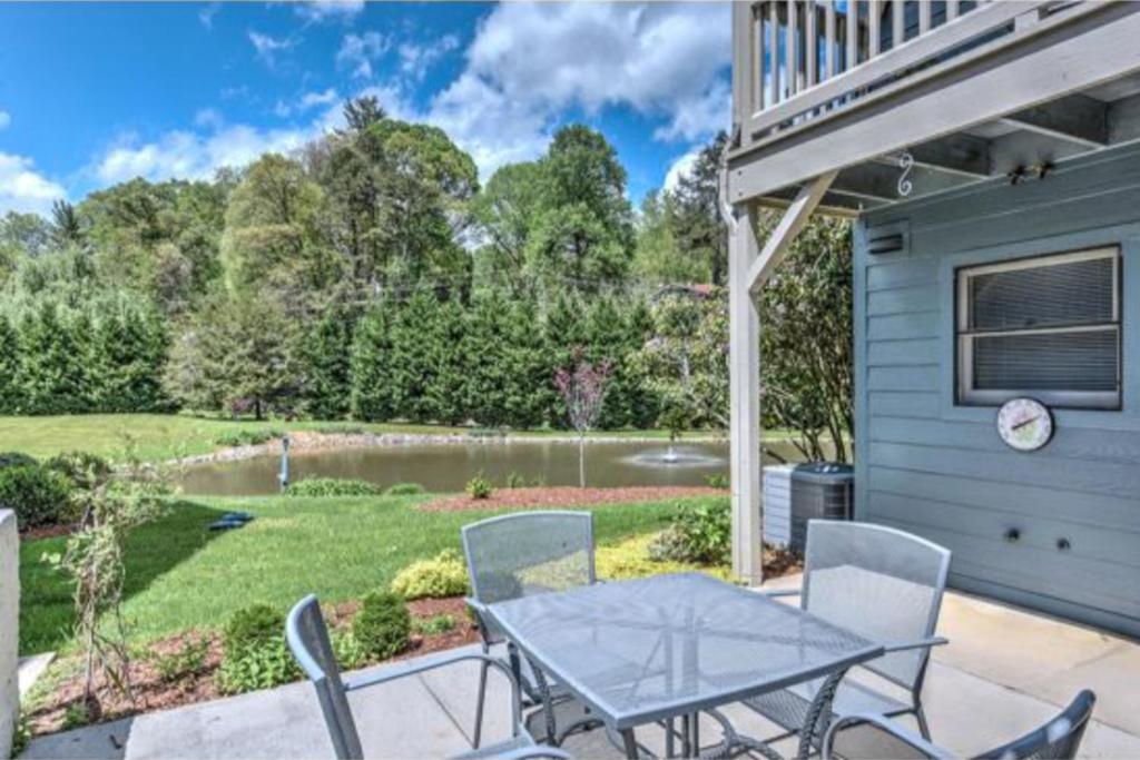 a patio with a table and chairs and a pond at Beehive Condo in Lake Junaluska