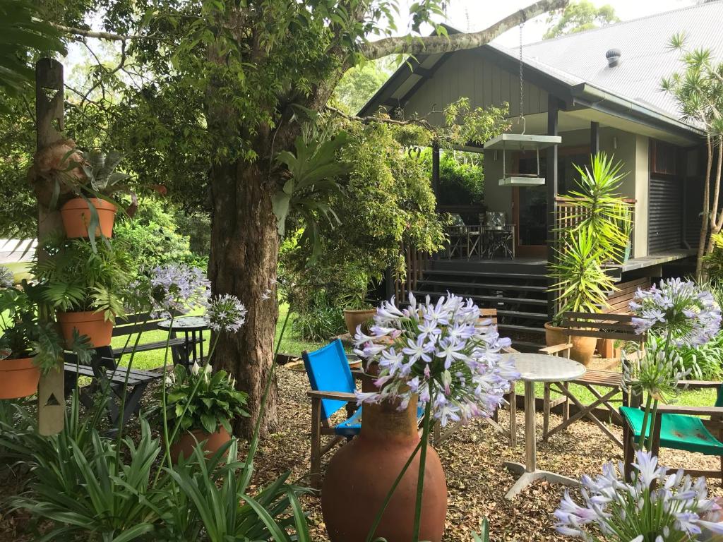 a garden with flowers and tables and a house at PK illusions in Maleny