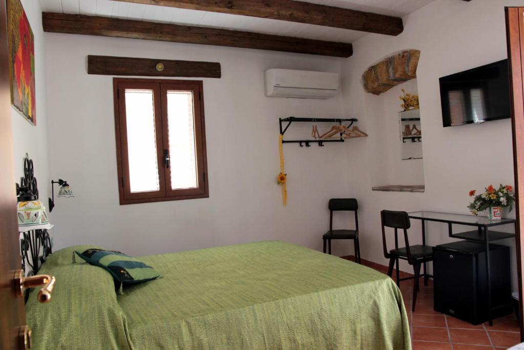 a bedroom with a bed and a table and a window at La Casa del Geko in Cefalù