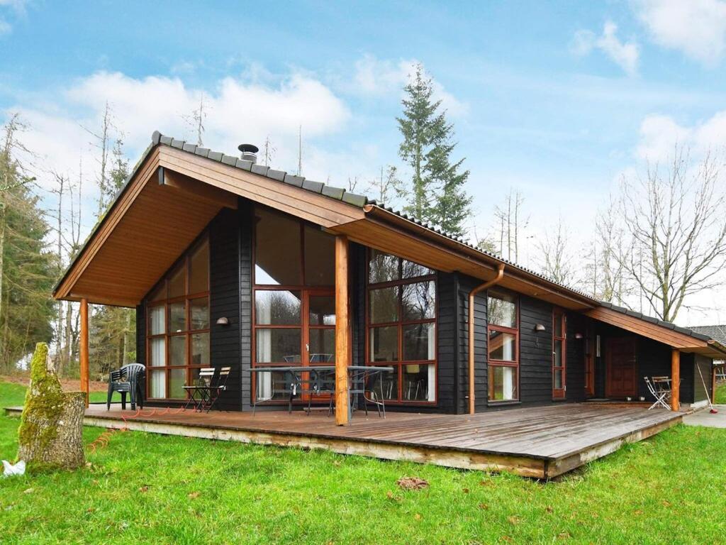a house with a large wooden deck in a field at 8 person holiday home in Skals in Hjarbæk