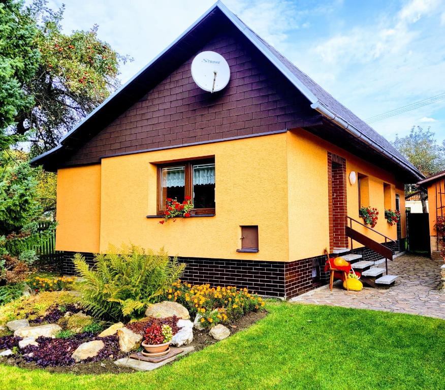 a yellow house with a clock on the side of it at Chaloupka u Splavu in Loučná nad Desnou
