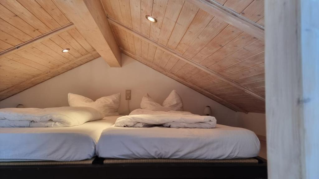 2 bedden in een zolderkamer met houten plafonds bij FeWo an der Ostsee Nr. 3 in Rerik