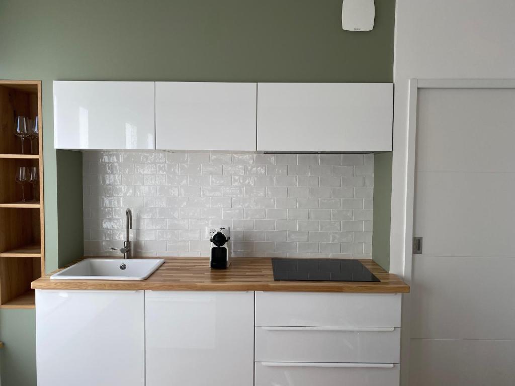 una cocina con armarios blancos y fregadero en Superbe appartement Moderne Hyper centre de Vittel en Vittel