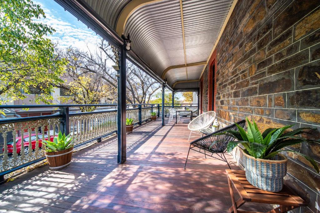 einen Balkon mit Bänken und Pflanzen an einer Ziegelwand in der Unterkunft Archer St Heart of North Adelaide Balcony 65TV in Adelaide