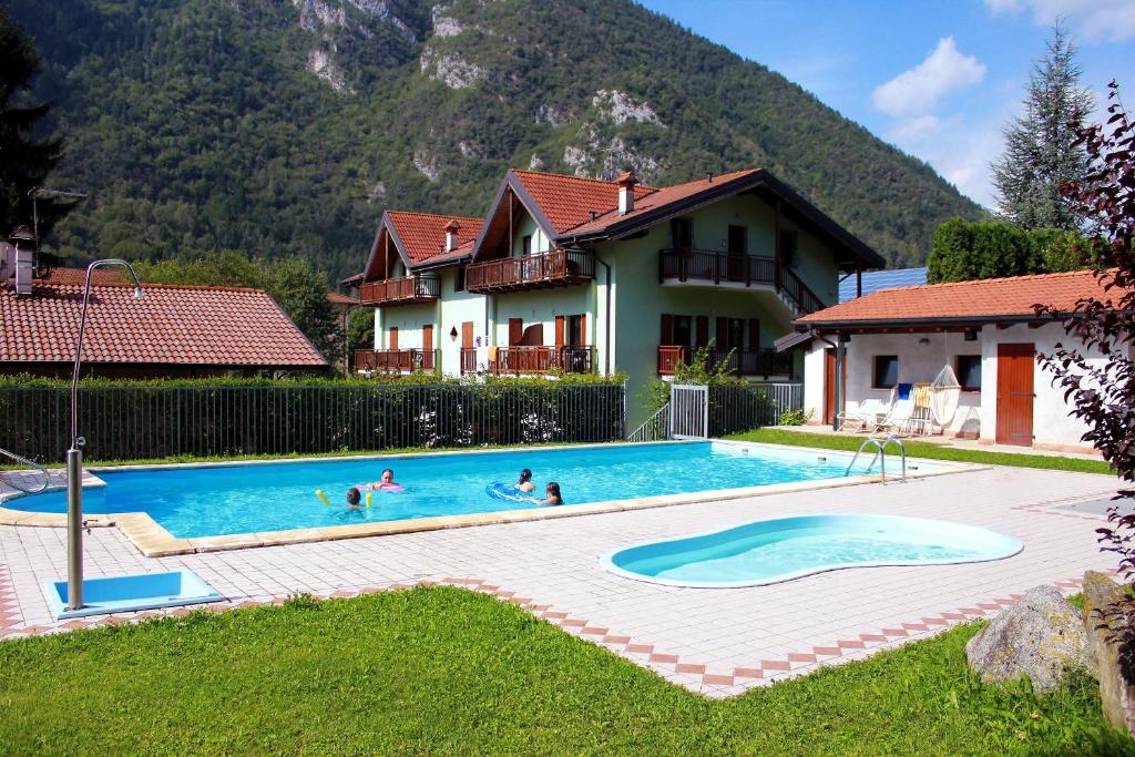 a group of people in a swimming pool in front of a house at Residence Filanda in Ledro