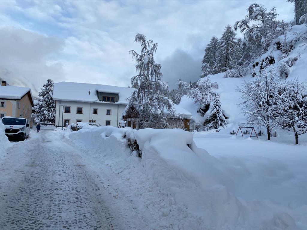 a snow covered road in front of a house at Stimmungsvolle Loftwohnung im Künstlerviertel in Susch in Sur