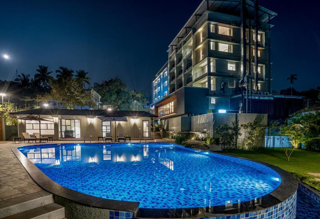 a swimming pool in front of a building at night at Oshin Hotel in Wayanad