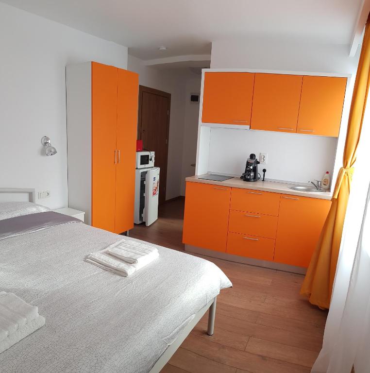a kitchen with orange cabinets and a bed in a room at Apartament 4 Budiu in Târgu-Mureş