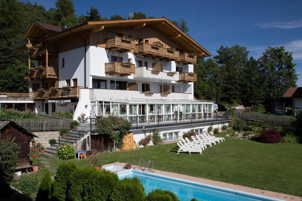 a large building with a swimming pool in front of it at Naturhotel Edelweiss in Terento