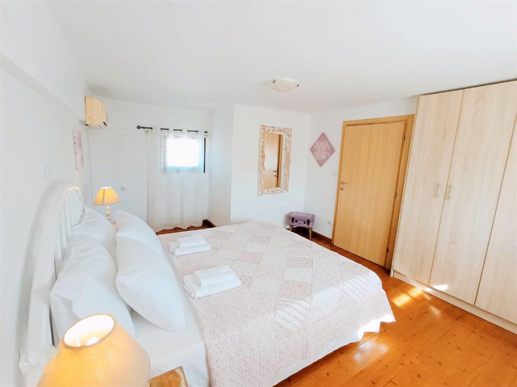 una camera con letto bianco e pavimento in legno di Villas and apartments on a private farm, only 1 km away from the beach! a Lefkogeia