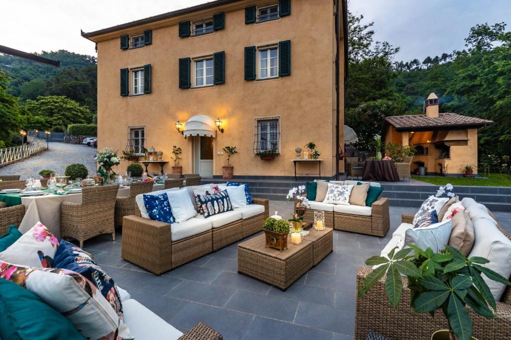 un patio avec des canapés et des tables en face d'un bâtiment dans l'établissement Casolare dei Colli, Panoramic Private Pool, Lavish Interiors and a Gourmet Kitchen, à Camaiore