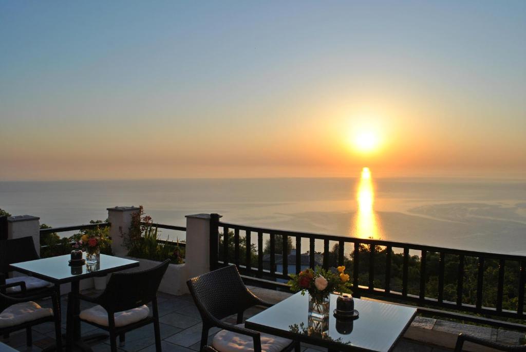 a view of the sunset from a patio with tables and chairs at Archontiko Elda in Agios Dimitrios