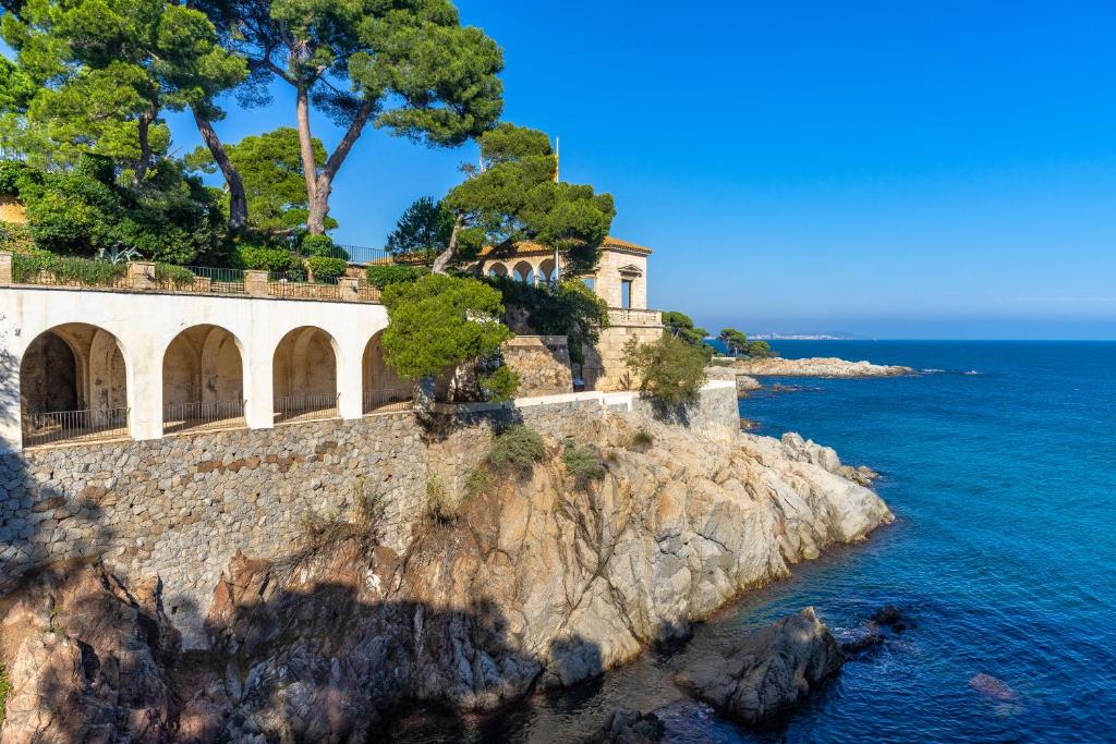 a house on a cliff next to the ocean at Hostal de la Gavina GL - The Leading Hotels of the World in S'Agaro